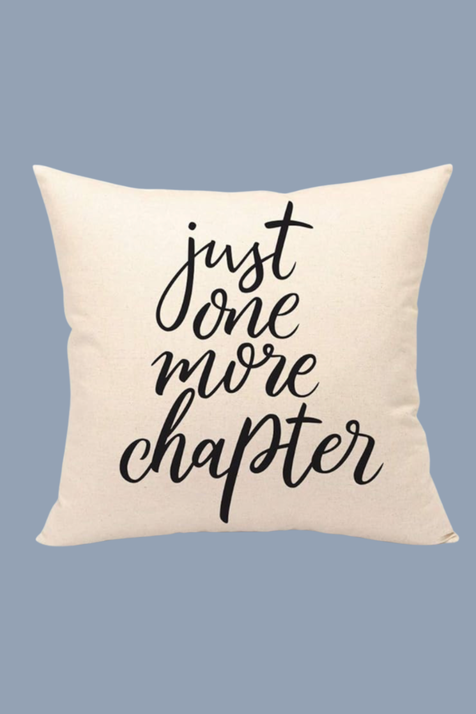 Decorative pillow with black script that says “just one more chapter,” ideal for reading nooks