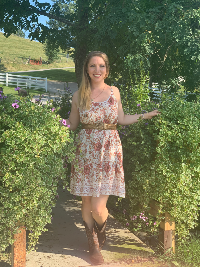 Woman in floral dress and cowboy boots standing in a garden, representing fun, down-to-earth book club vibes