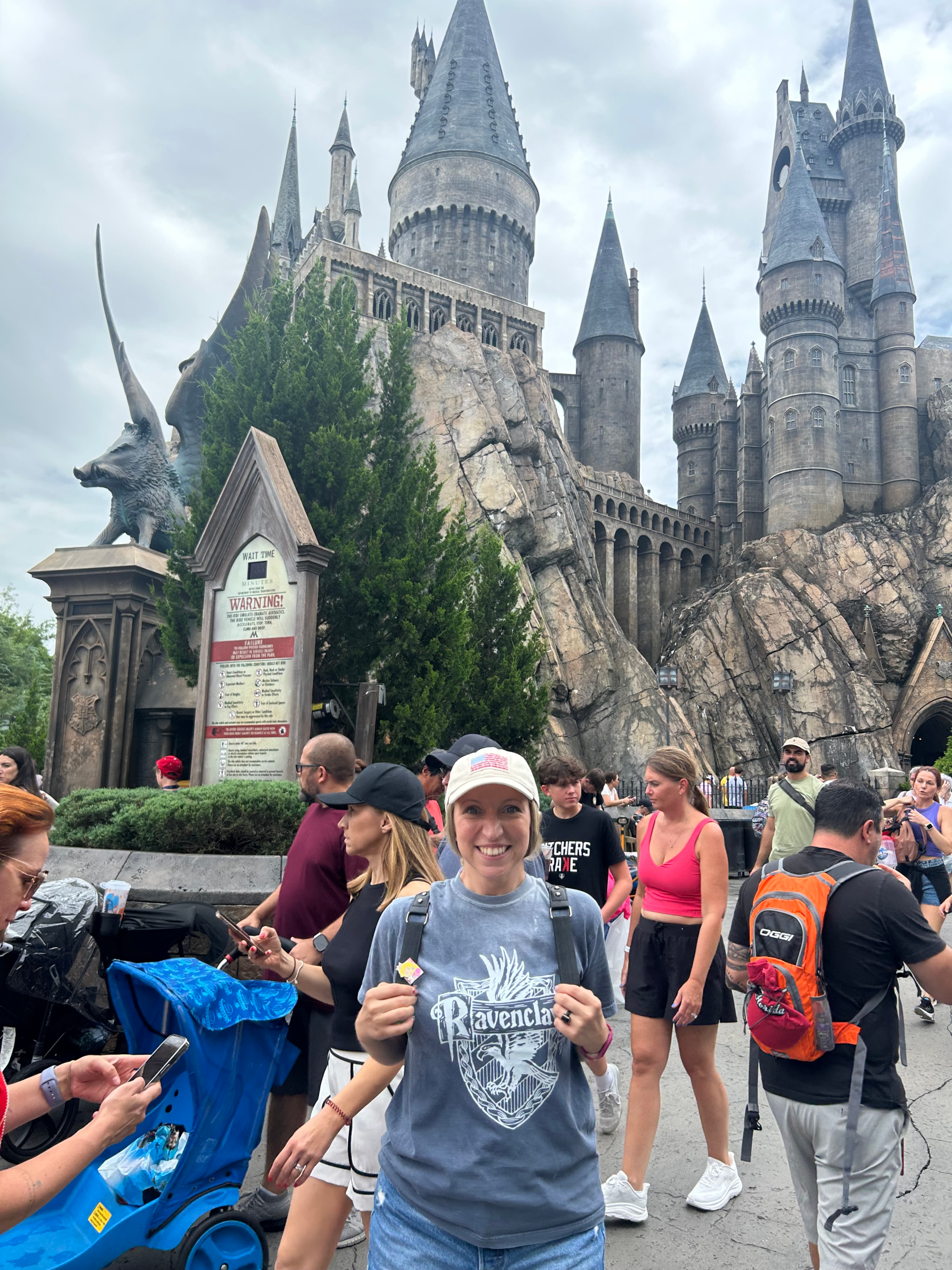 Woman in Ravenclaw shirt posing in front of Hogwarts Castle at Universal Studios Orlando