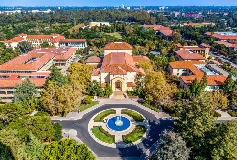 Aerial view of Stanford University campus with red-roofed buildings and central fountain, the academic setting featured in Deep End by Ali Hazelwood, a sports romance novel.